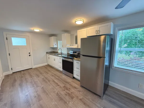 a kitchen with granite countertop stainless steel appliances a refrigerator cabinets and wooden floor