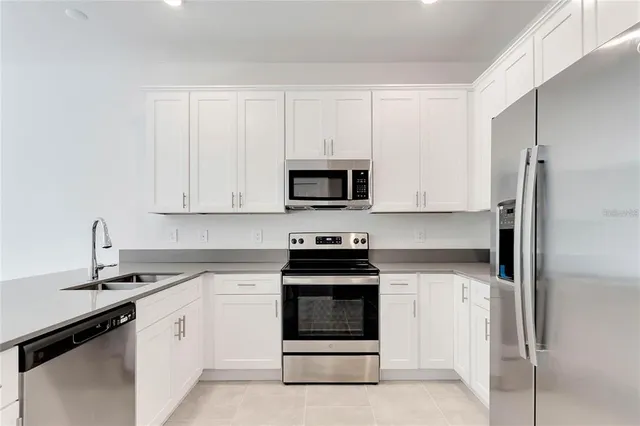 a kitchen with white cabinets and stainless steel appliances