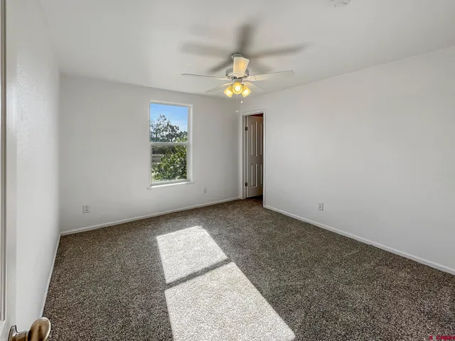 an empty room with a window and a ceiling fan