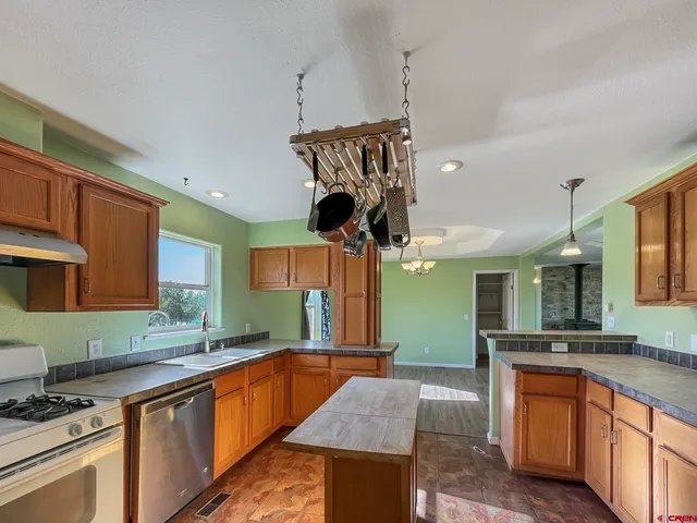 a kitchen with stainless steel appliances granite countertop a sink a stove and a wooden cabinets