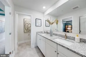 a bathroom with a granite countertop double vanity sink and a mirror