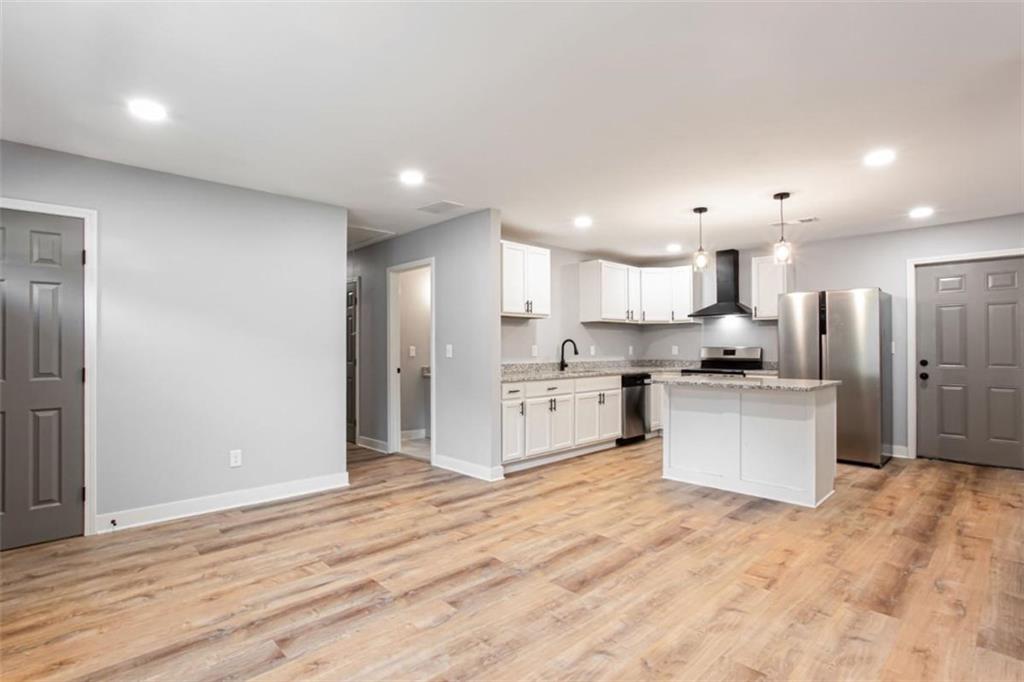 3652 Sweetbriar Circle Lithia Springs, GA 30122 - Photo 11 of 30 a large kitchen with stainless steel appliances kitchen island a sink dishwasher a refrigerator and white cabinets with wooden floor