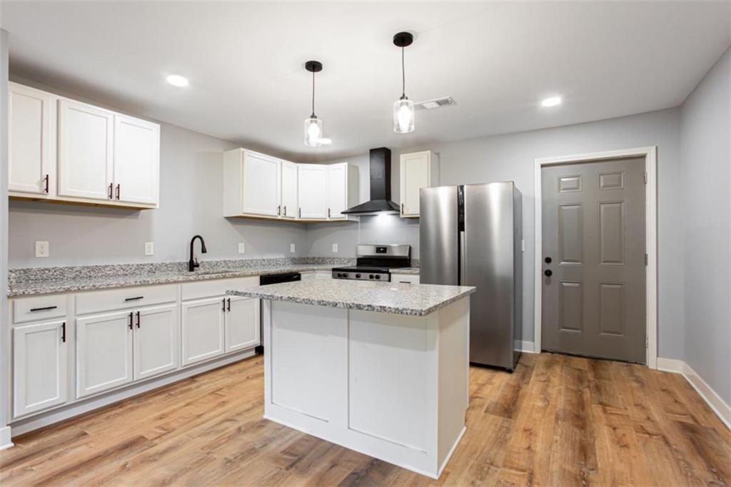 3652 Sweetbriar Circle Lithia Springs, GA 30122 - Photo 12 of 30 a kitchen with stainless steel appliances granite countertop a sink a stove a refrigerator and island with wooden floor