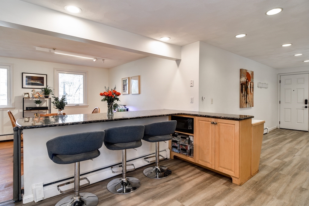 248 Liberty Square Road Boxborough, MA 01719 - Photo 5 of 31 a kitchen with stainless steel appliances granite countertop a refrigerator a stove a sink dishwasher and a dining table with wooden floor