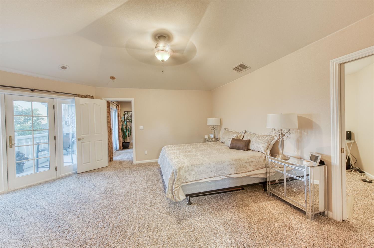 14374 Killarney Drive Madera, CA 93636 - Photo 50 of 56 a spacious bedroom with a bed and a chandelier