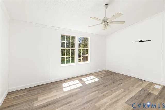 an empty room with wooden floor fan and windows