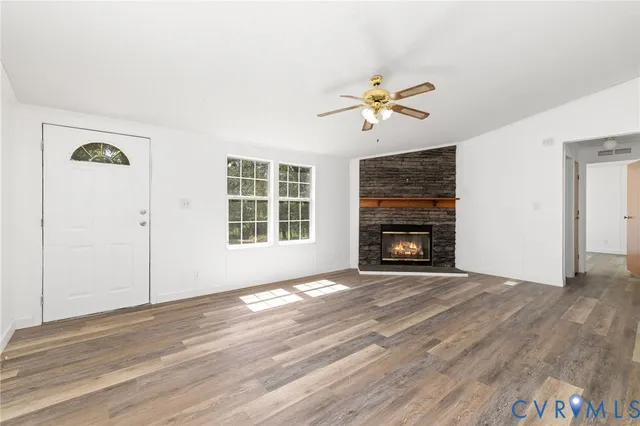 an empty room with windows fireplace and a kitchen view