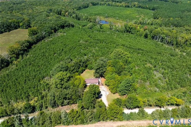 an aerial view of residential house with outdoor space and trees all around