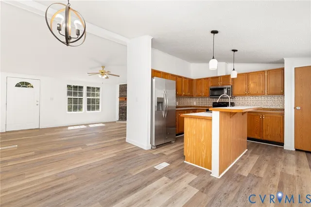 a open kitchen with a refrigerator a stove top oven a sink and dishwasher with wooden floor