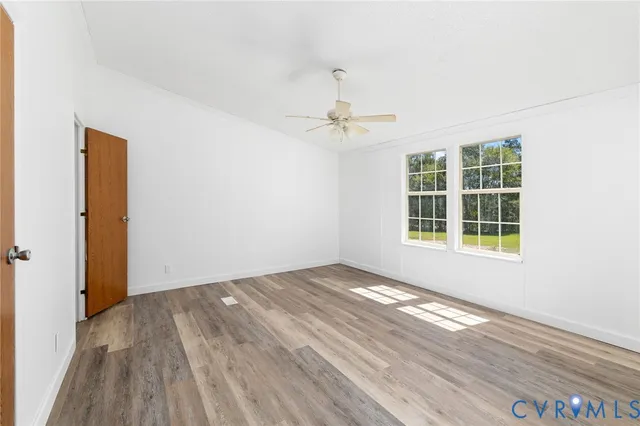 a view of empty room with wooden floor and fan