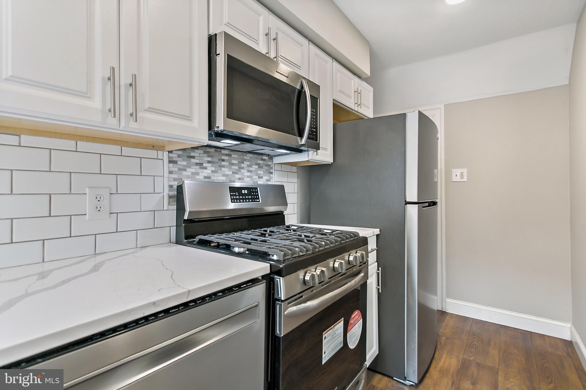 7158 Radbourne Road Upper Darby, PA 19082 - Photo 8 of 15 a kitchen with stainless steel appliances granite countertop a stove microwave and refrigerator