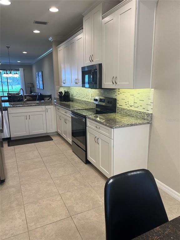 13737 Messina Loop, Unit 101 Bradenton, FL 34211 - Photo 4 of 25 a kitchen with stainless steel appliances granite countertop a stove a sink and a microwave