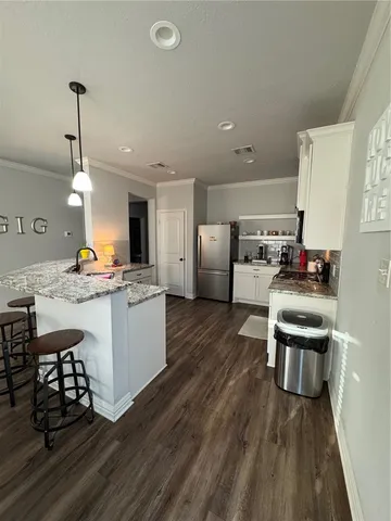 a kitchen with stainless steel appliances kitchen island granite countertop a refrigerator a stove a sink dishwasher a dining table and chairs with wooden floor