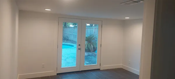 a view of an empty room with wooden floor and door
