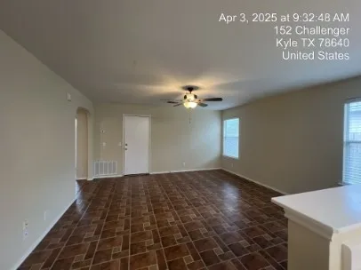 a view of an empty room with window and chandelier fan