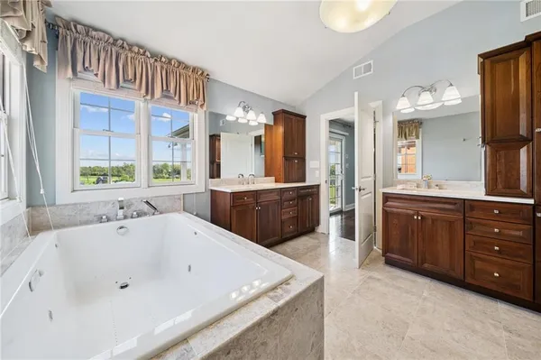 a spacious bathroom with a tub sink and mirror