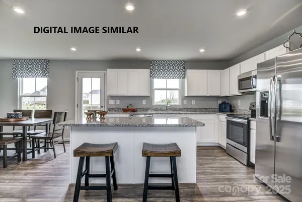 a kitchen with stainless steel appliances granite countertop a stove a sink a microwave a island with a dining table and chair