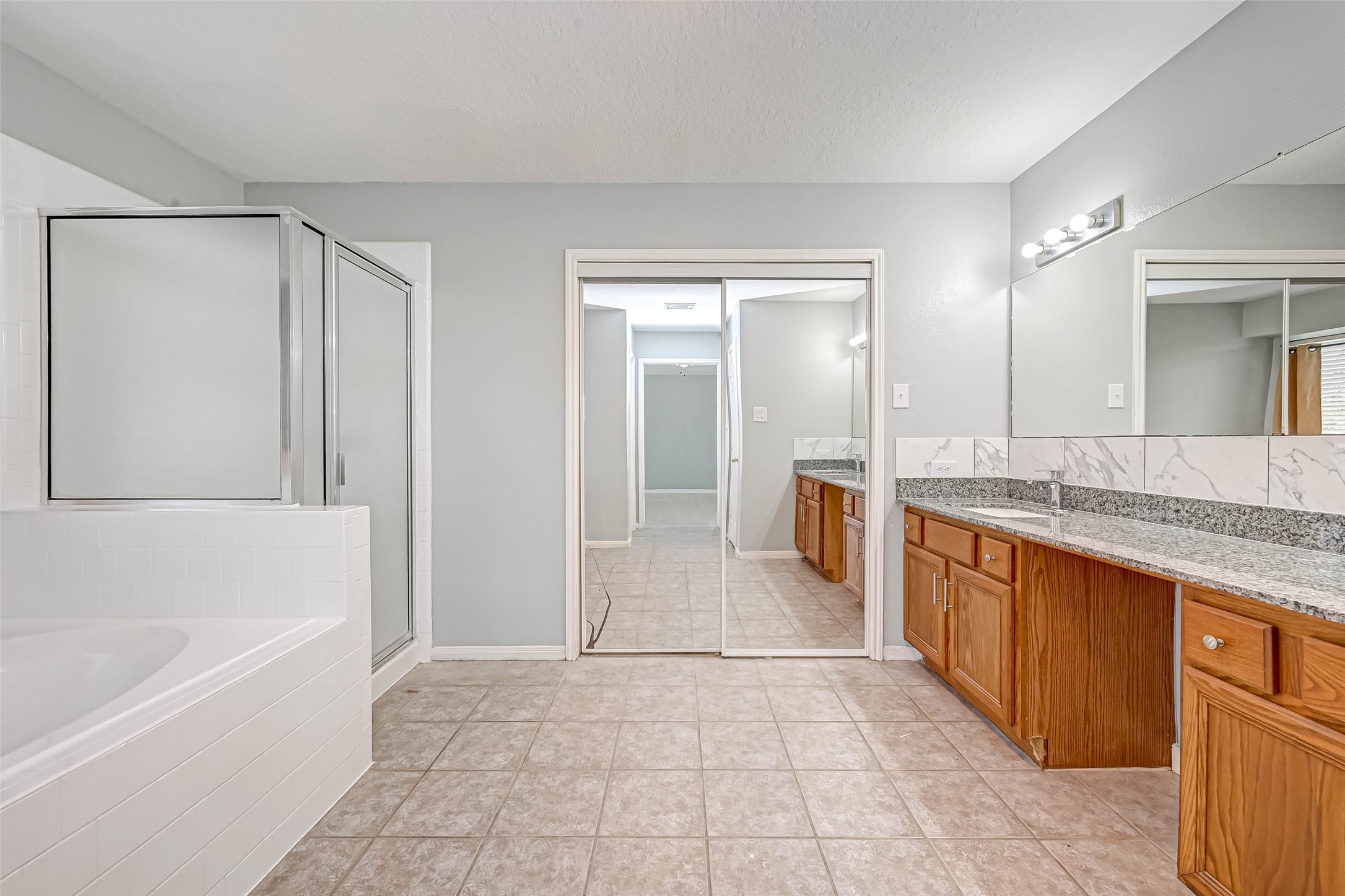 7520 Vincik Ehlert Road Rosenberg, TX 77471 - Photo 35 of 46 a large spacious bathroom with a granite countertop double vanity sink a mirror and a bathtub