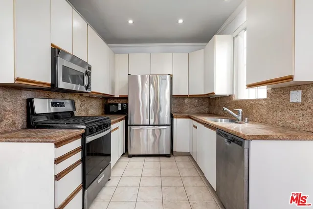 a kitchen with stainless steel appliances granite countertop a stove top oven a sink and a refrigerator