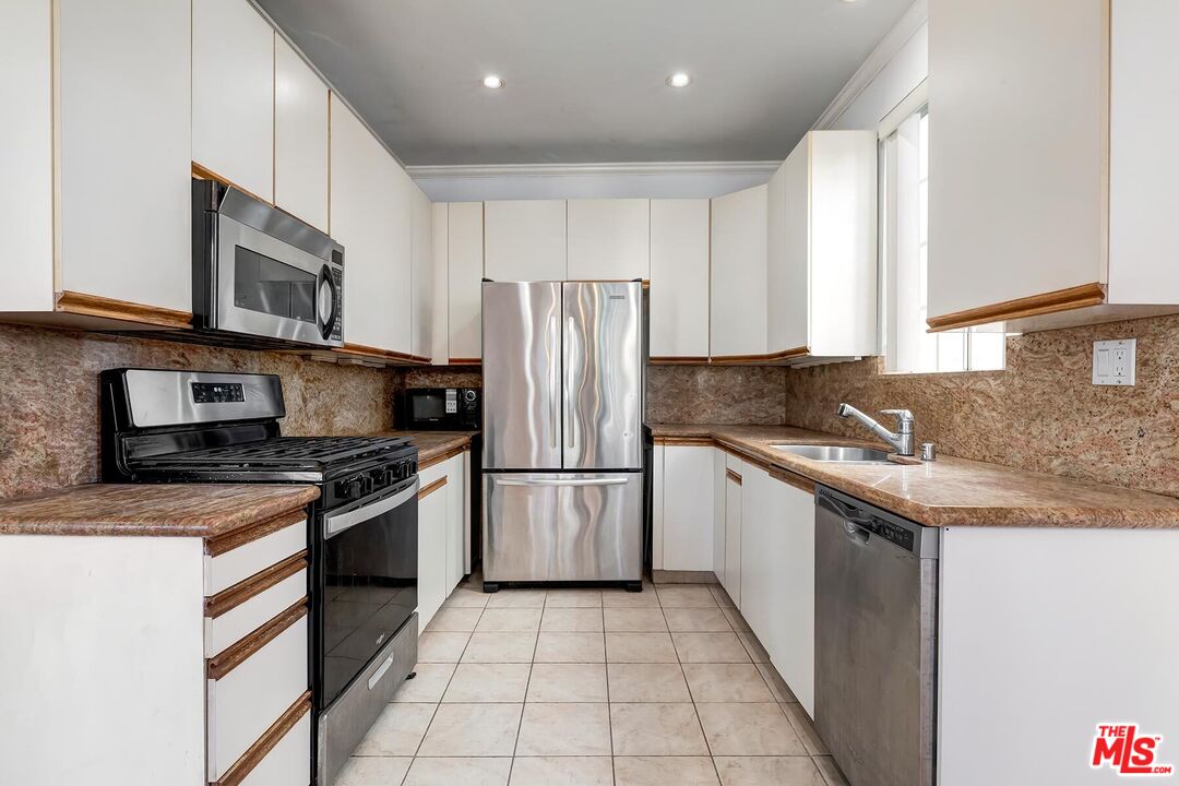 1169 Wellesley Avenue, Unit 101 Los Angeles, CA 90049 - Photo 13 of 26 a kitchen with stainless steel appliances granite countertop a stove top oven a sink and a refrigerator