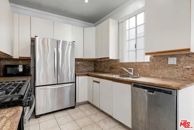 a kitchen with stainless steel appliances granite countertop a refrigerator a sink and white cabinets