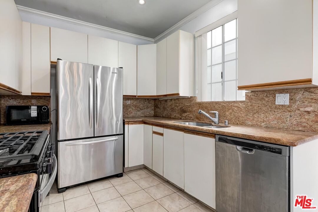 1169 Wellesley Avenue, Unit 101 Los Angeles, CA 90049 - Photo 14 of 26 a kitchen with stainless steel appliances granite countertop a refrigerator a sink and white cabinets