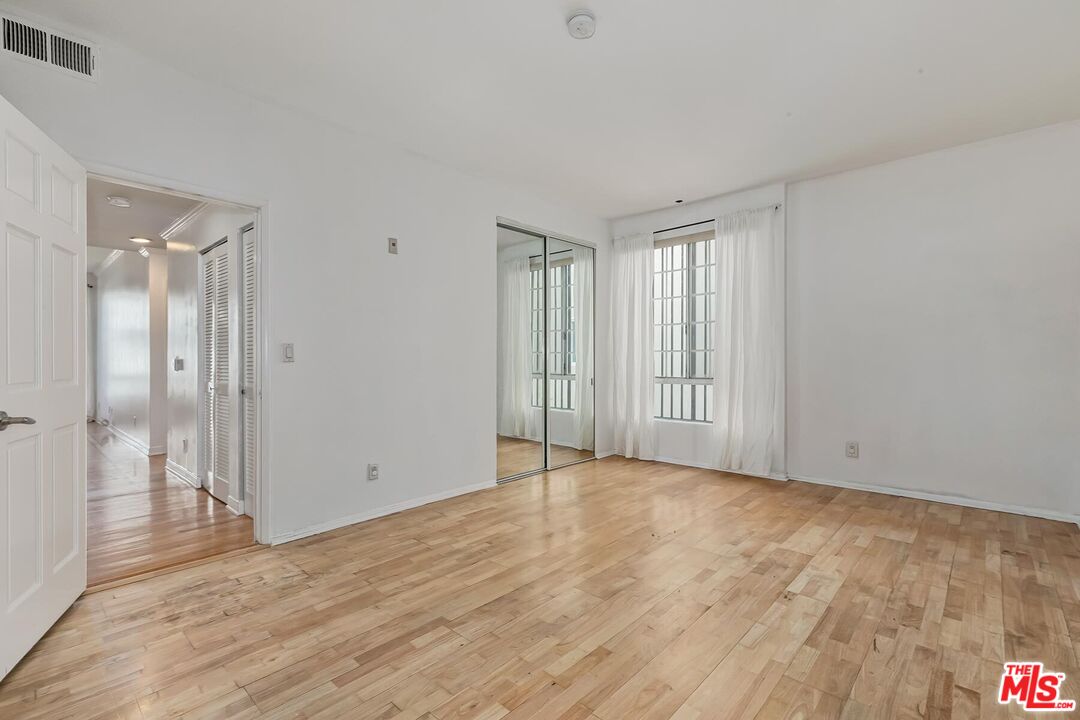 1169 Wellesley Avenue, Unit 101 Los Angeles, CA 90049 - Photo 17 of 26 a view of an empty room with wooden floor and a window