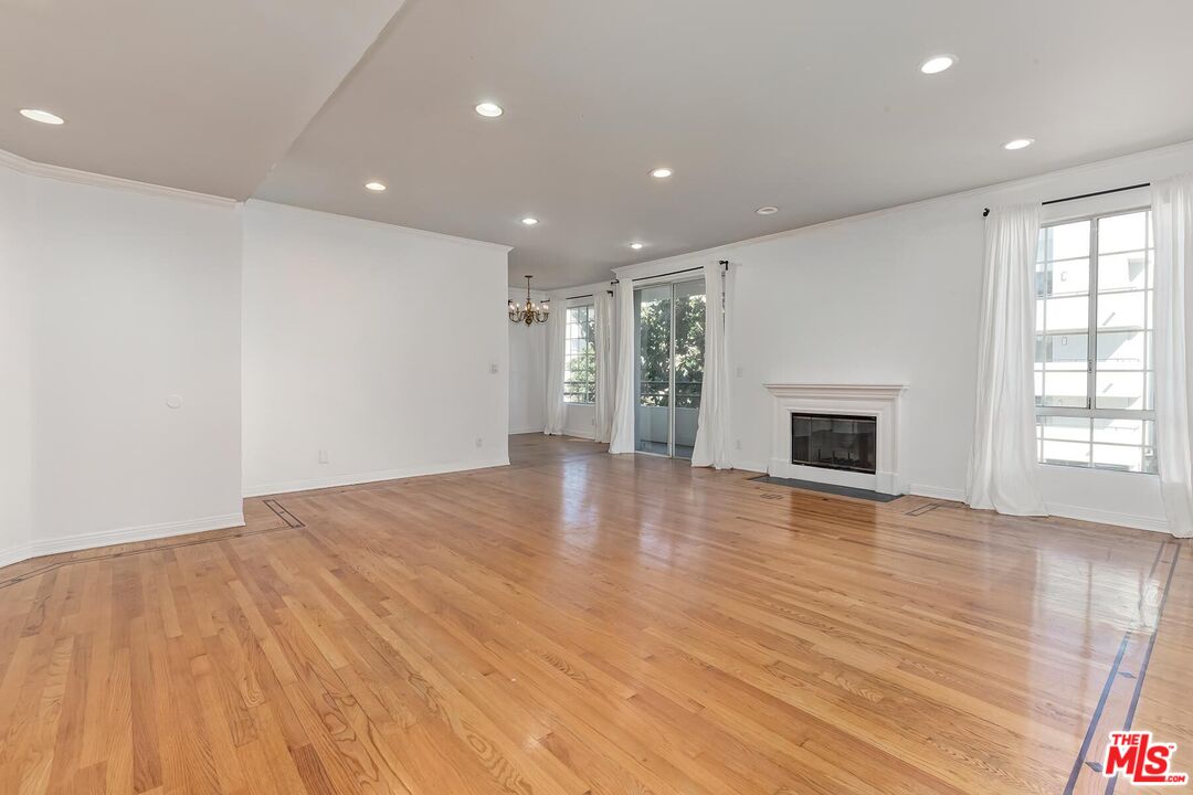 1169 Wellesley Avenue, Unit 101 Los Angeles, CA 90049 - Photo 4 of 26 an empty room with wooden floor and fireplace
