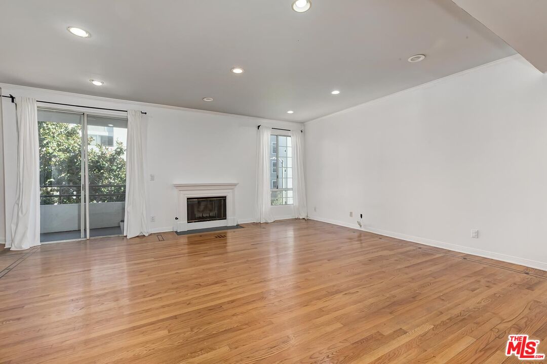 1169 Wellesley Avenue, Unit 101 Los Angeles, CA 90049 - Photo 6 of 26 an empty room with wooden floor and a fireplace