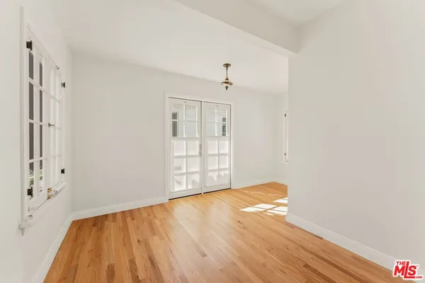 a view of an empty room with wooden floor and a window