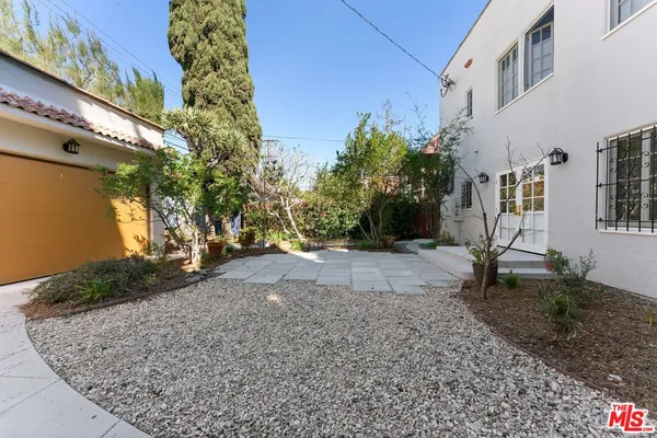 a view of a yard with plants and a bench