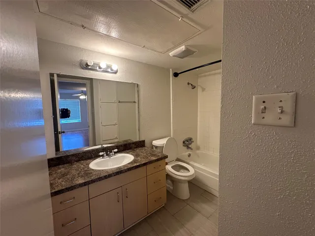 a bathroom with a granite countertop sink toilet and mirror