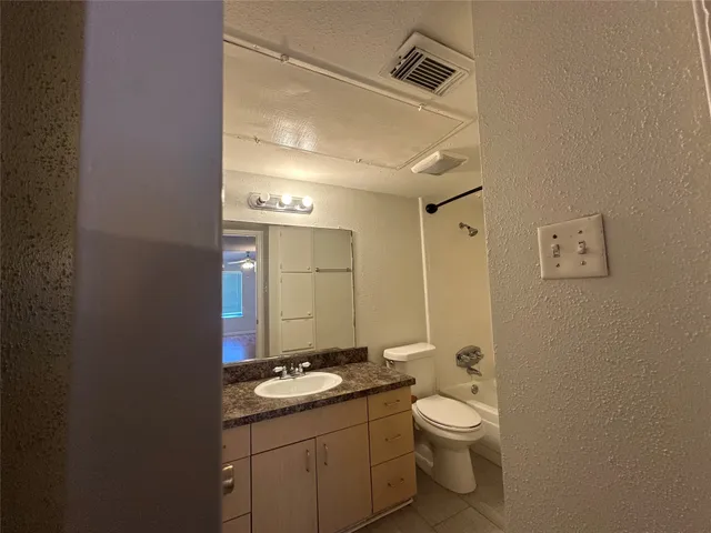 a bathroom with a granite countertop toilet a sink and mirror