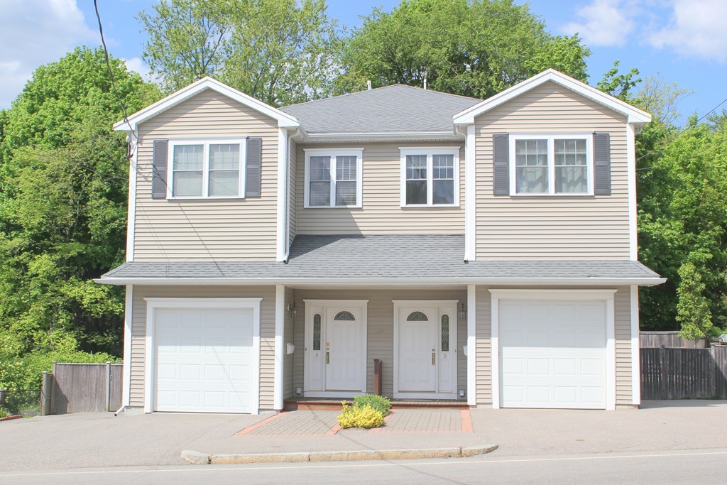 a view of a white house with large windows and a small yard