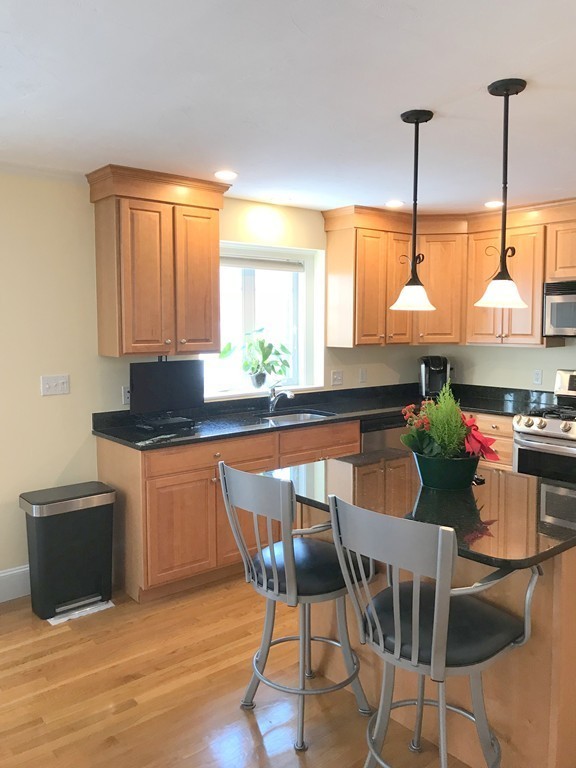 343 Quarry Street, Unit 2 Quincy, MA 02169 - Photo 2 of 30 a kitchen with stainless steel appliances granite countertop wooden cabinets a stove a sink and a microwave