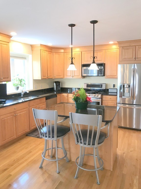343 Quarry Street, Unit 2 Quincy, MA 02169 - Photo 3 of 30 a kitchen with stainless steel appliances kitchen island granite countertop a table and chairs in it
