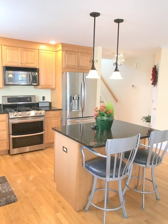343 Quarry Street, Unit 2 Quincy, MA 02169 - Photo 4 of 30 a kitchen with stainless steel appliances kitchen island granite countertop a table chairs and a view of living room