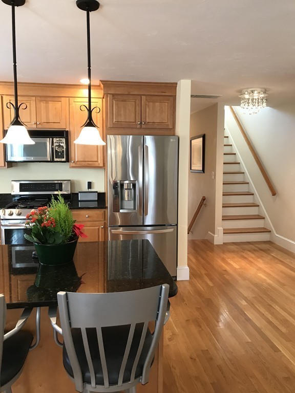 343 Quarry Street, Unit 2 Quincy, MA 02169 - Photo 5 of 30 a kitchen with stainless steel appliances kitchen island granite countertop a table chairs in it and wooden floors