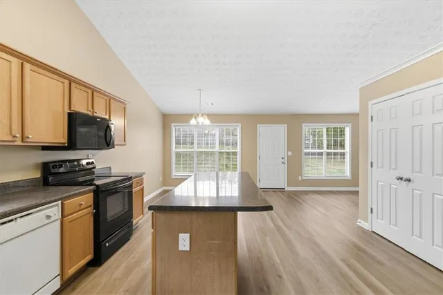 a kitchen with granite countertop a stove a sink a microwave and wooden floors