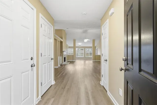 a view of a hallway with wooden floor and a bathroom