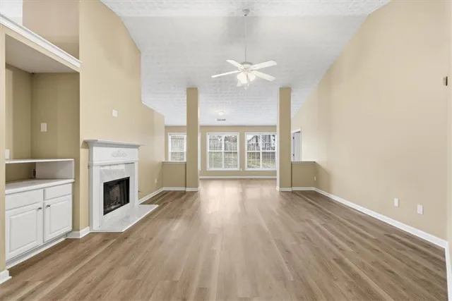 an empty room with wooden floor fireplace and windows