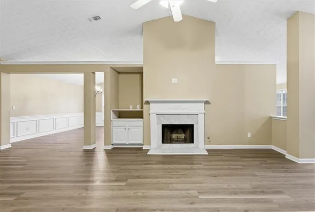 a view of an empty room with wooden floor and a fireplace