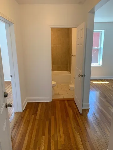 an empty room with wooden floor and a bathroom