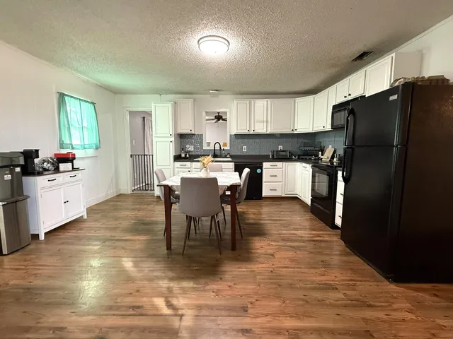 a kitchen with stainless steel appliances a dining table chairs stove refrigerator and cabinets