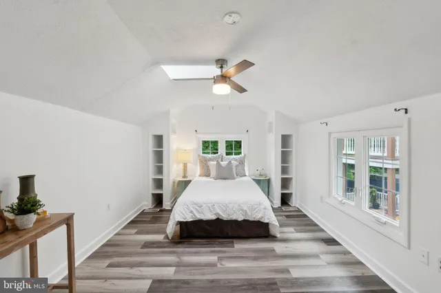 a spacious bedroom with a large bed a chandelier and windows