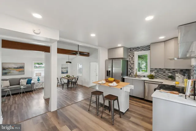 a open dining room with stainless steel appliances kitchen island granite countertop a table chairs and a refrigerator