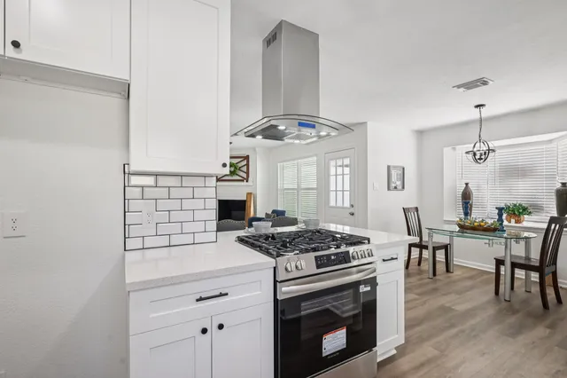 a kitchen with stainless steel appliances a stove a table and chairs