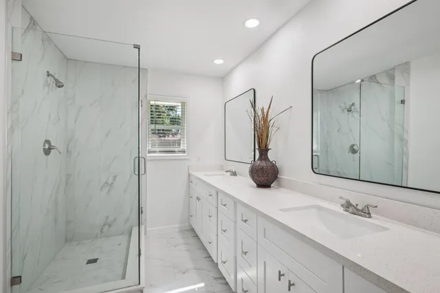 a bathroom with double sink shower and mirror