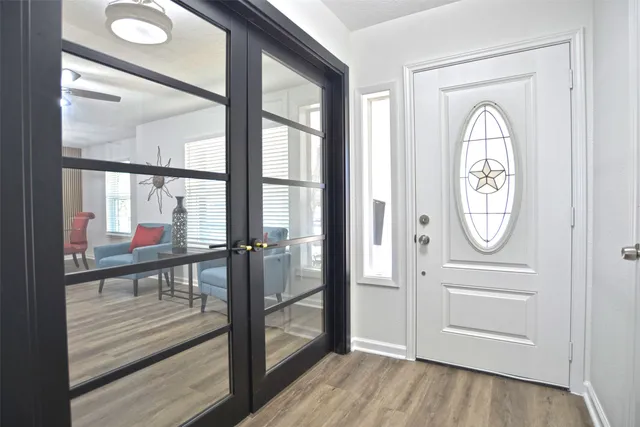 a view of a hallway with wooden floor door and windows