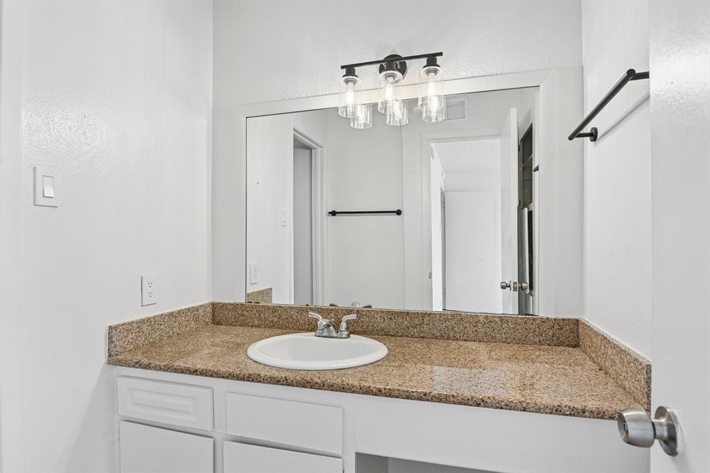 5300 Keller Springs Road, Unit 2055 Dallas, TX 75248 - Photo 14 of 24 Bathroom vanity featuring an integrated sink, a speckled countertop, and white cabinetry